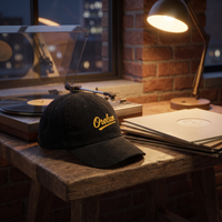 Casquette en velours côtelé noire Orelsan posée près d'une platine vinyle, ambiance loft urbain