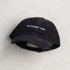 Casquette dad hat velours côtelé noire « Pas évident hein » posée à plat, design complet