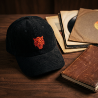 Casquette en velours côtelé noire brodée tête de tigre, CHT'M Boutique, mise en scène avec vinyles vintage et carnet en cuir sur bois de noyer foncé