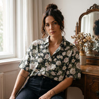 Chemise homme manches courtes noire à pivoines blanches portée par une femme assise à une coiffeuse vintage devant un miroir ancien - CHT'M Boutique
