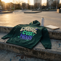 hoodie boxy Gen Z « L'avenir c'est nous » vert sapin posé sur les marches d'un skatepark au coucher du soleil – CHT'M Boutique