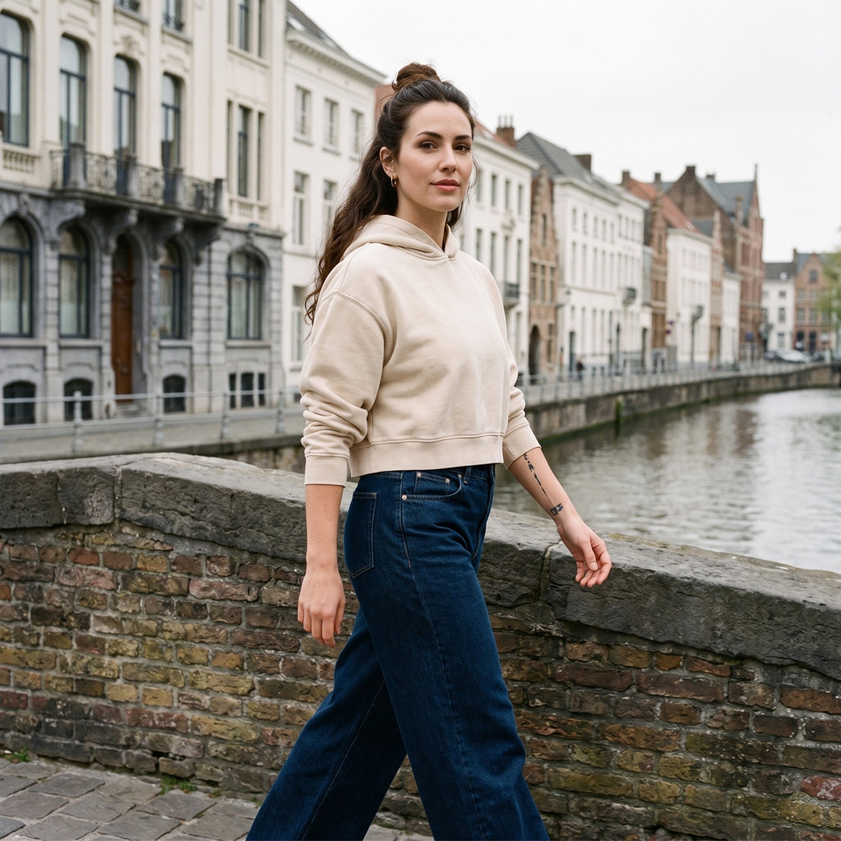 Hoodie crop top femme délavé abricot clair porté sur un pont en Belgique