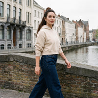 Hoodie crop top femme délavé abricot clair porté sur un pont en Belgique