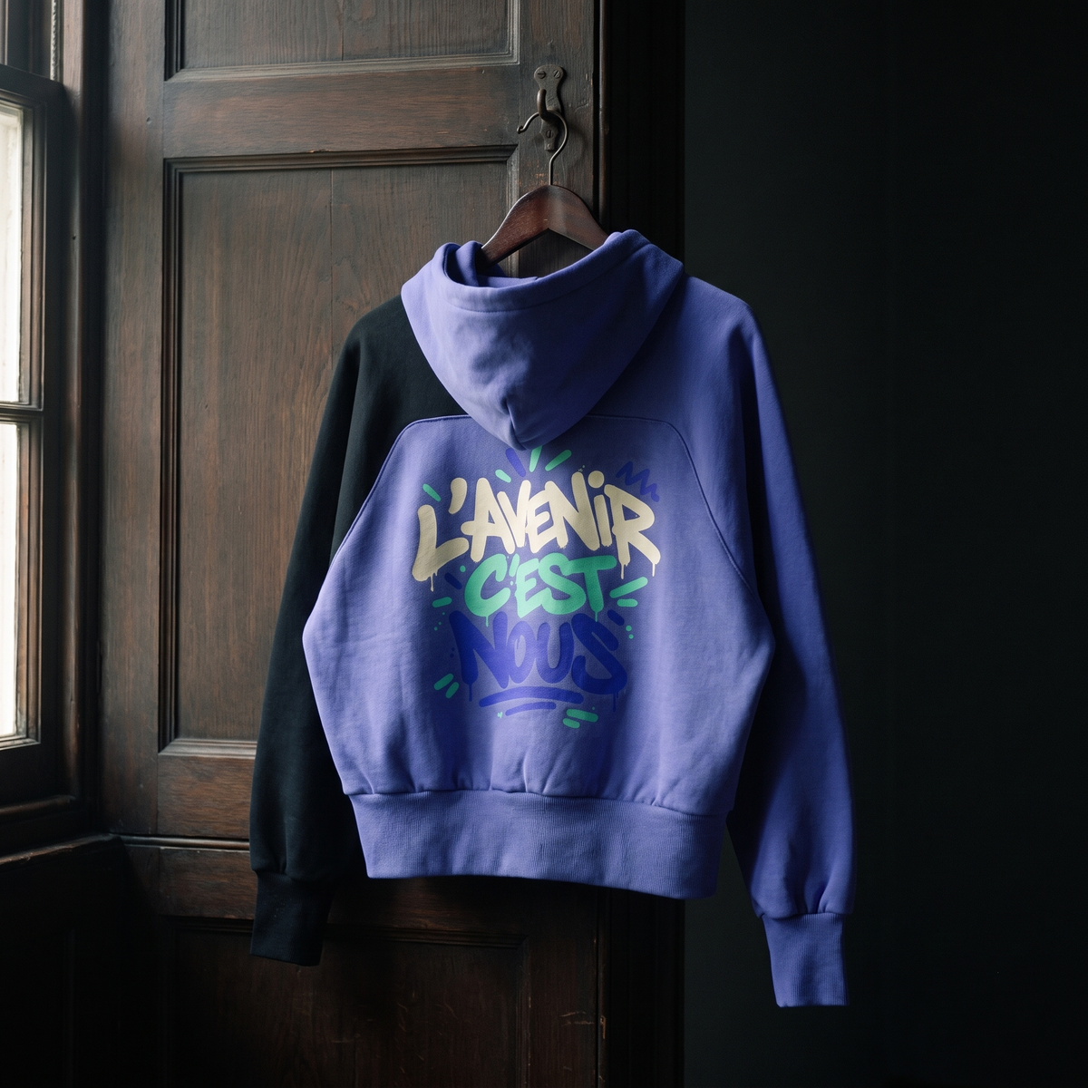 Hoodie Gen Z bicolore violet et noir L'avenir c'est nous suspendu sur un cintre, grand print dans le dos