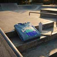 Hoodie oversize Gen Z bleu acier plié sur les marches d'un skatepark