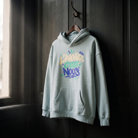 Hoodie oversize Gen Z bleu ciel L'avenir c'est nous suspendu sur un cintre en bois