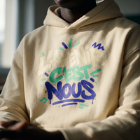 Gros plan du graffiti L'avenir c'est nous sur le hoodie oversize vanille porté