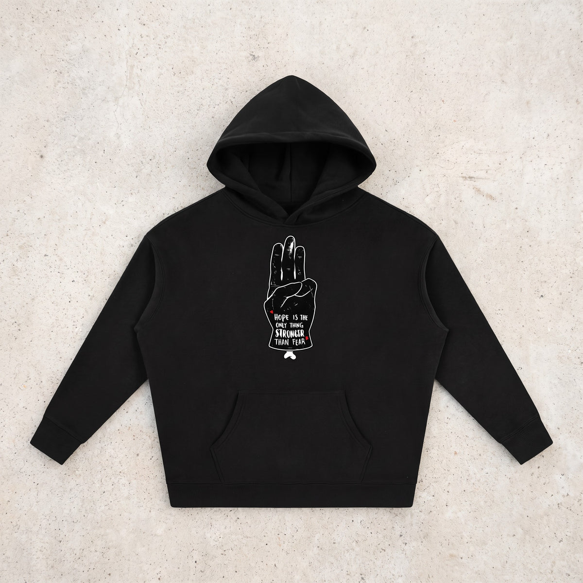 Hoodie oversize original noir Hope posé à plat sur béton, design salut à trois doigts complet