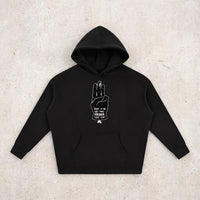 Hoodie oversize original noir Hope posé à plat sur béton, design salut à trois doigts complet