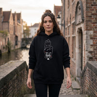 Femme portant le sweat à capuche oversize noir Hope au bord d'un canal belge, design salut à trois doigts