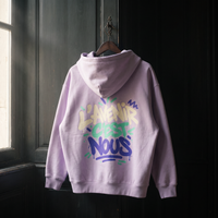 Hoodie zippé boxy Gen Z lilas suspendu sur un cintre, grand graffiti L'avenir c'est nous dans le dos