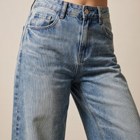 Gros plan du jean large femme original bleu délavé : taille, coupe et texture du denim