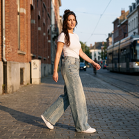 Femme portant le jean wide leg original bleu jean délavé dans une rue pavée belge