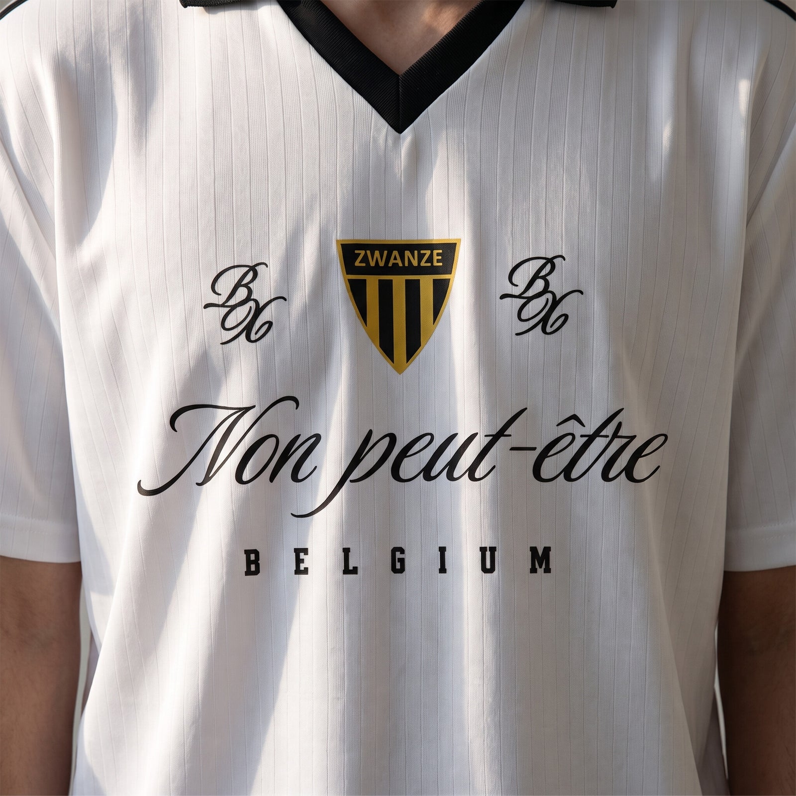 Gros plan du design Non Peut-Être et du blason Zwanze sur le maillot de foot streetwear