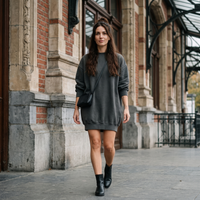 Femme portant la robe sweat oversize délavée gris foncé devant une gare belge