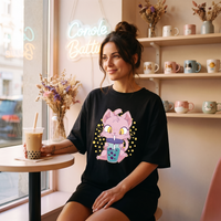 Robe t-shirt oversize noire chat kawaii buvant un bubble tea, portée dans un salon de bubble tea aux couleurs pastel