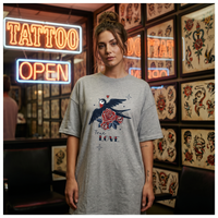 Femme portant la robe t-shirt oversize grise imprimé hirondelle et rose True Love dans un salon de tatouage vintage