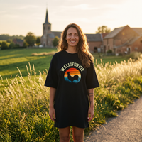Robe t-shirt oversize noire Wallifornie au coq wallon sur soleil rétro, portée au coucher du soleil dans la campagne wallonne
