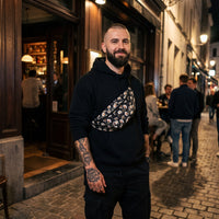 Sac banane fleurs blanches fond noir porté par un homme, look streetwear en Belgique | CHT'M Boutique