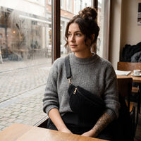 Sac bandoulière moumoute effet teddy noir porté par une femme, look streetwear en Belgique | CHT'M Boutique