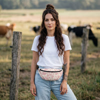 Sac banane imprimé vache rose pâle porté par une femme, look streetwear en Belgique | CHT'M Boutique