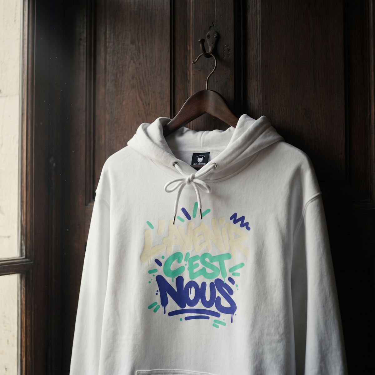 sweat à capuche Gen Z « L'avenir c'est nous » blanc suspendu sur un cintre en bois – sweat Gen Z original CHT'M