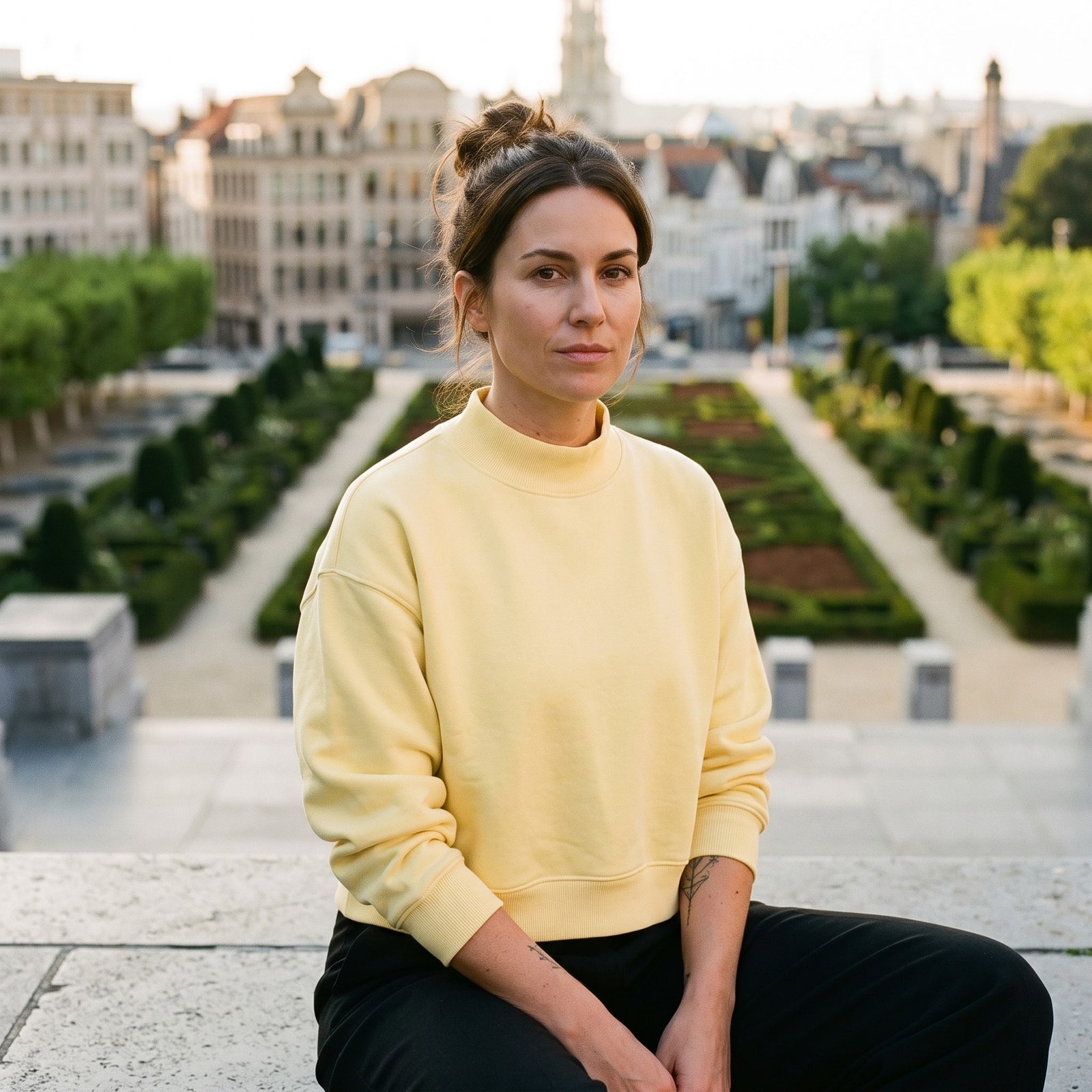 Femme portant le sweat crop col montant original CHT'M jaune, assise au Mont des Arts à Bruxelles