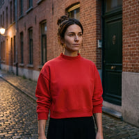 Femme portant le sweat crop col montant original CHT'M rouge, dans une rue pavée de Bruxelles
