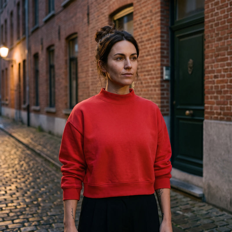 Femme portant le sweat crop col montant original CHT'M rouge, dans une rue pavée de Bruxelles