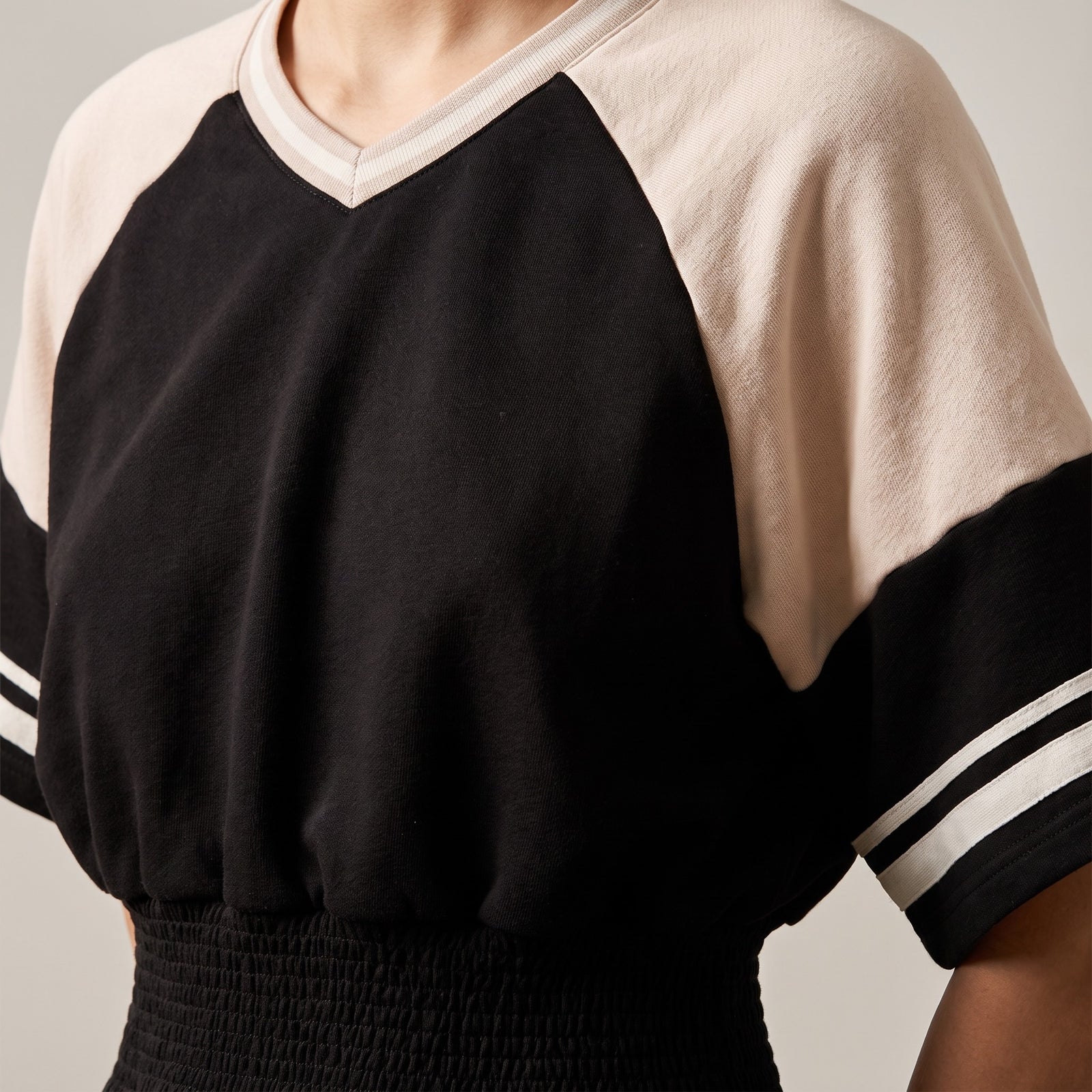 Gros plan du sweat crop raglan original femme noir / abricot : coupe, col et texture du tissu