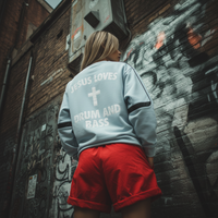 Femme portant le sweat Drum and Bass bleu ciel, vue de dos devant un mur graffiti