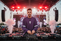 DJ en sweat Drum and Bass violet aux platines sur scène de festival