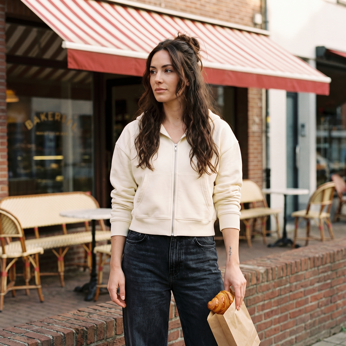 Femme portant le sweat zippé crop top crème devant une boulangerie belge