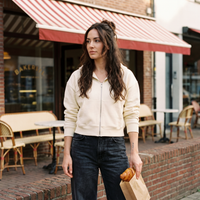 Femme portant le sweat zippé crop top crème devant une boulangerie belge