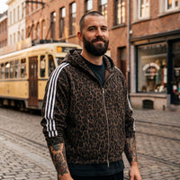 Hoodie léopard café zippé porté par un homme dans une rue belge avec tram