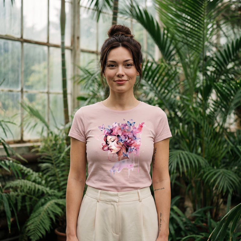 T-shirt femme rose poudré porté dans une serre : imprimé aquarelle visage de femme et papillons