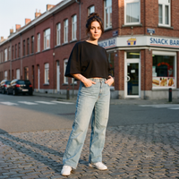 Femme portant le t-shirt manches chauve-souris noir dans une rue belge