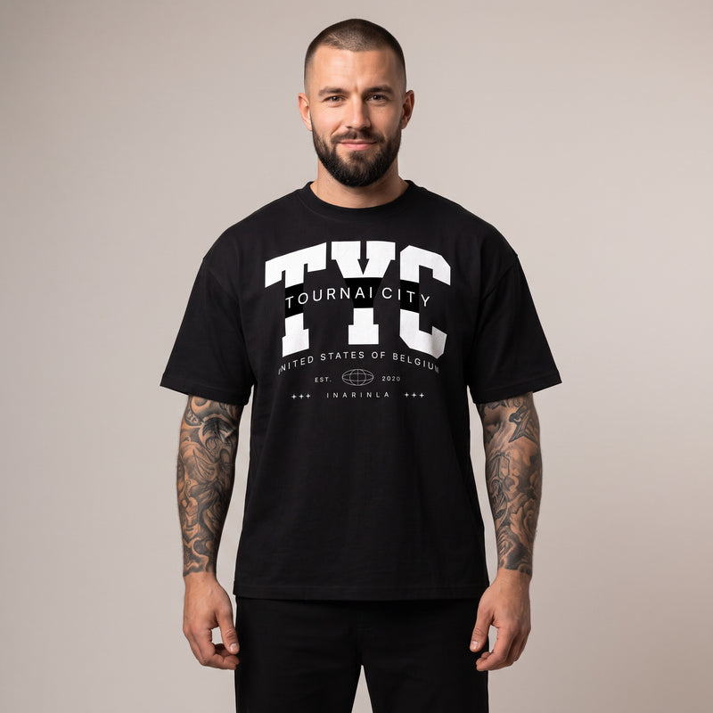 Homme portant le t-shirt oversized noir Tournai City à l'imprimé varsity TYC blanc
