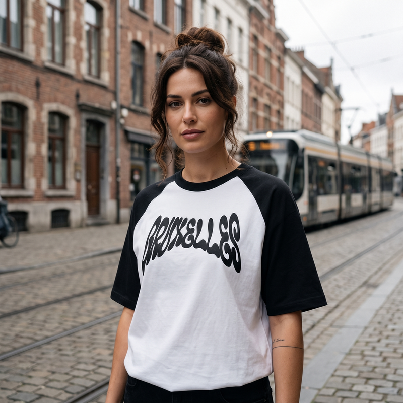 T-shirt belge oversized BRUXELLES blanc et noir porté par une femme dans une rue pavée avec tram, Bruxelles