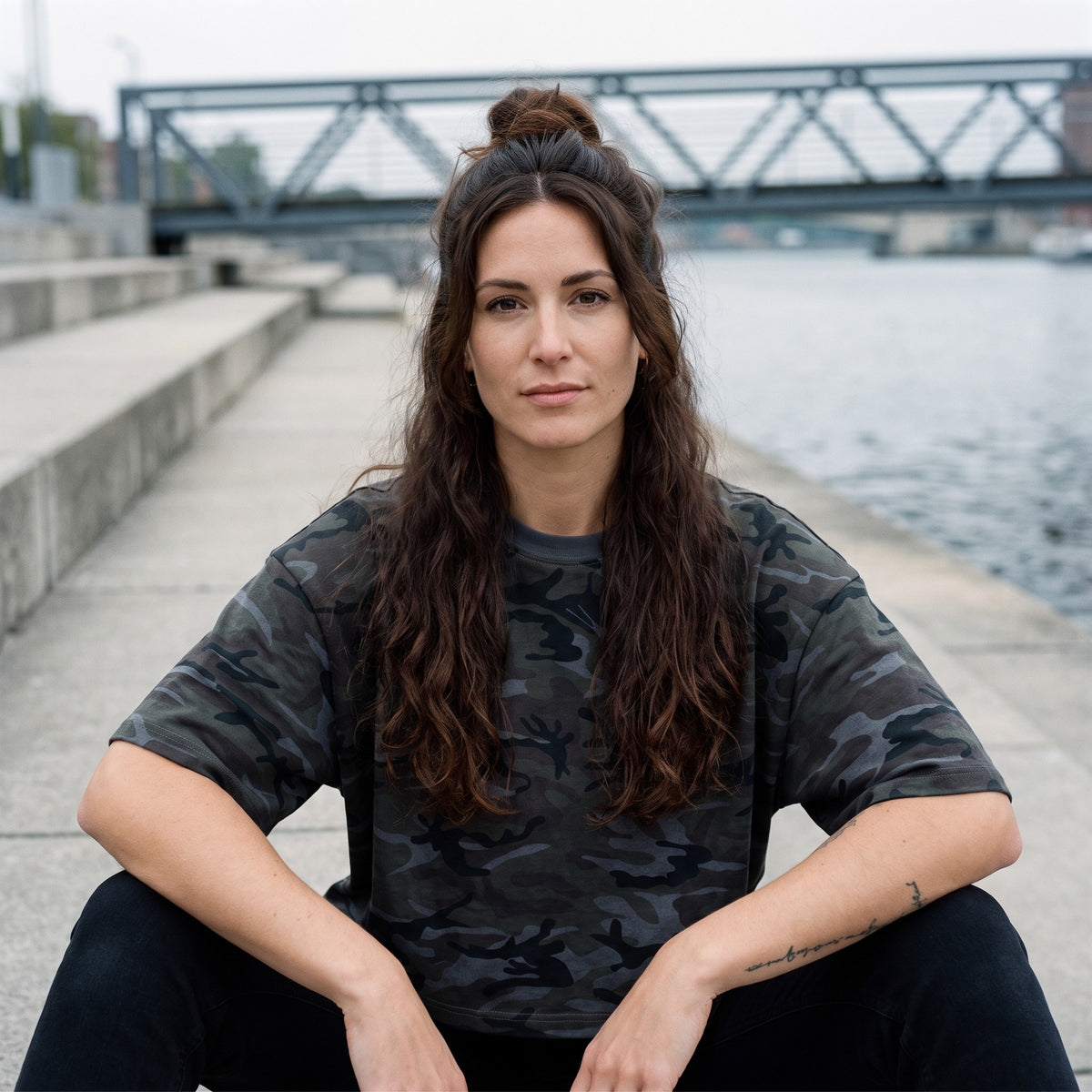 T-shirt camouflage boxy gris CHT'M porté par une femme assise sur un quai en Belgique