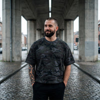 T-shirt camouflage boxy gris CHT'M porté par un homme sous un pont en béton d'une ville belge