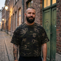 T-shirt camouflage boxy kaki CHT'M porté par un homme dans une rue en briques d'une ville belge