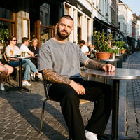 Homme portant le t-shirt délavé original gris en terrasse, look streetwear belge