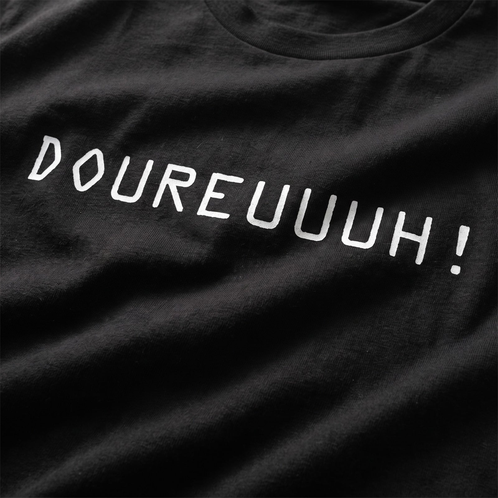 Gros plan du design Doureuuuh imprimé en blanc sur le t-shirt oversize noir