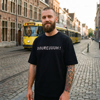 T-shirt original Doureuuuh noir porté par un homme dans une rue belge, tram en arrière-plan