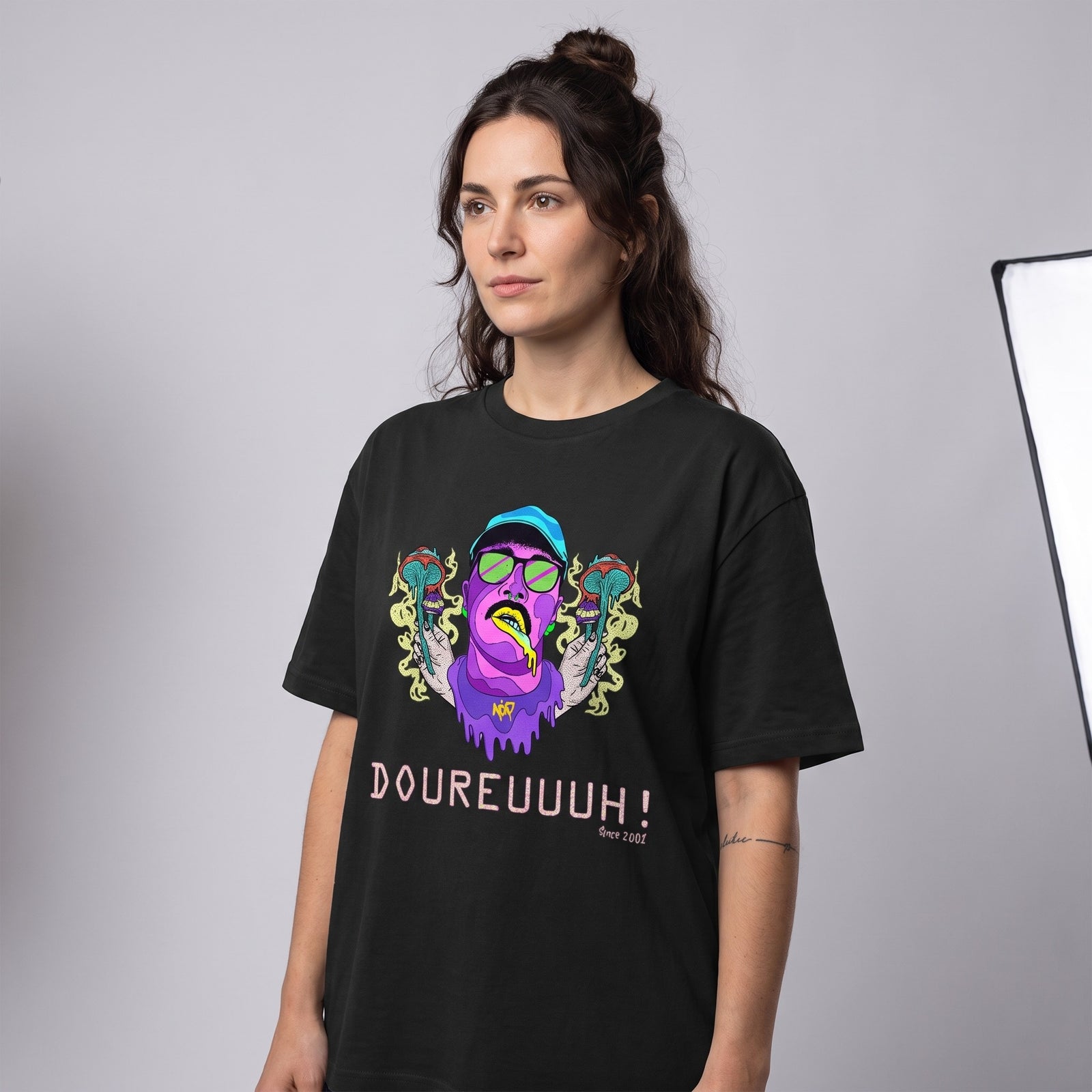 Photo studio d'une femme portant le t-shirt Dour Festival psychédélique noir DOUREUUUH ! Since 2001
