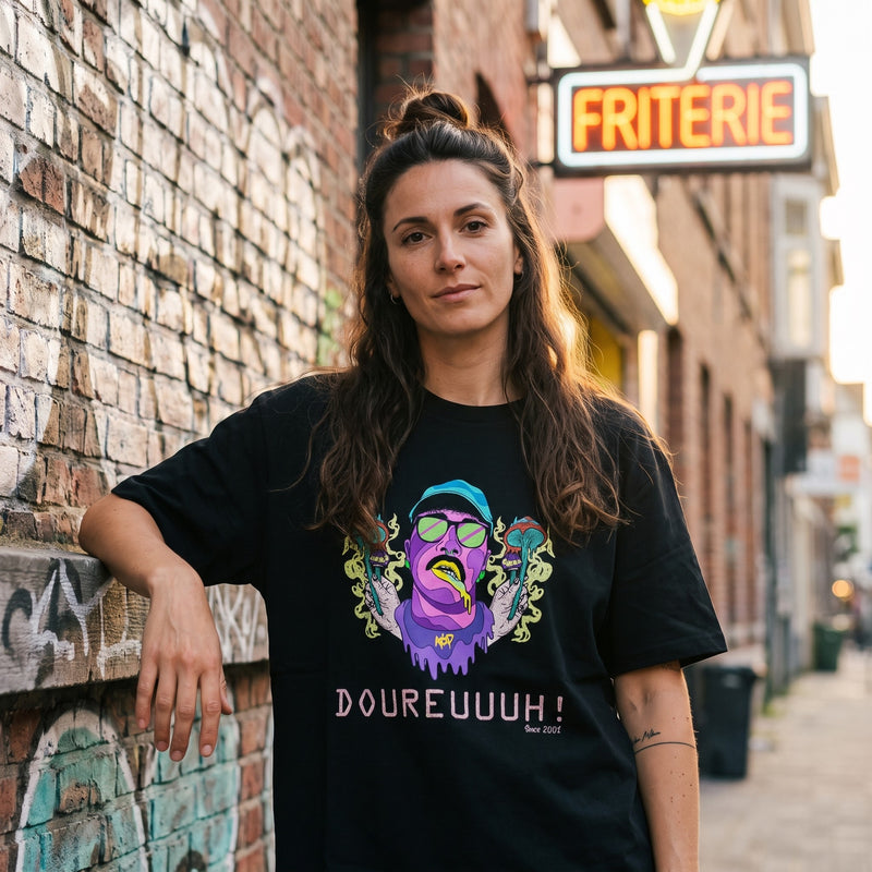 Femme en t-shirt festival psychédélique noir devant une friterie belge, look streetwear