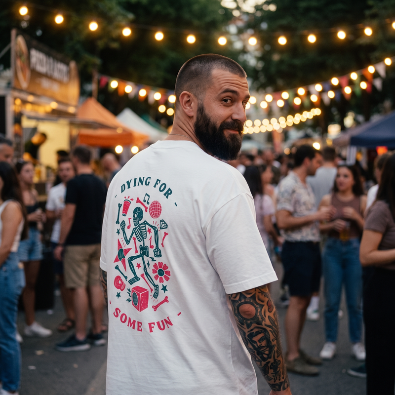 T-shirt oversized Dying For Some Fun blanc, dos imprimé squelette danseur, porté par un homme lors d'une fête de rue le soir