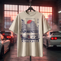 T-shirt oversized enfant Demonsta sable, imprimé voiture japonaise et soleil levant, présenté sur support dans un garage tuning éclairé au coucher de soleil