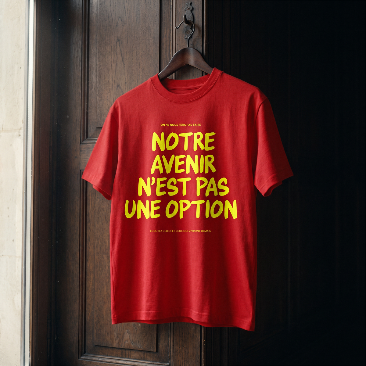 T-shirt Gen Z rouge « Notre avenir n'est pas une option », slogan jaune fluo, sur cintre en bois dans un intérieur sombre – t-shirt manif original CHT'M